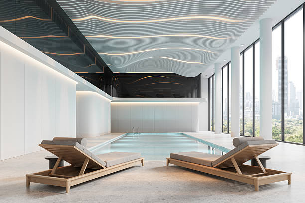 istock Modern luxury indoor pool interior with wavy ceiling design, lounge chairs and panoramic city view through glass walls in a bright relaxing setting. 3D Rendering 2214546696