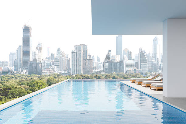 Rooftop infinity pool with clear blue water, modern exterior design, luxury lounge chairs on terrace, city skyline in background, calm summer concept, 3D Rendering