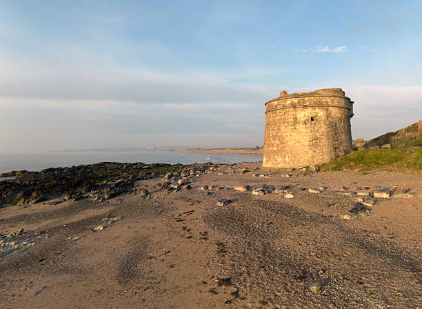 istock historic stone tower on a rocky beach at dawn 2214549393