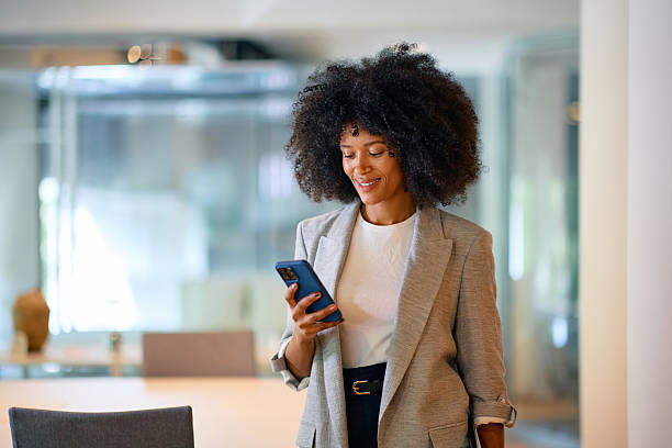 istock Smiling businesswoman using smartphone in modern office 2214551427