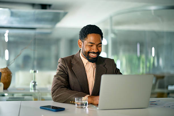 istock Smiling businessman working on laptop in modern office 2214551479