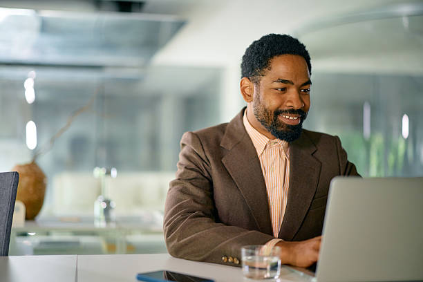 istock Smiling businessman working on laptop in modern office 2214551499