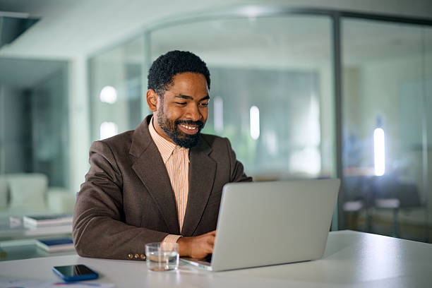 istock Smiling businessman working on laptop in modern office 2214551511