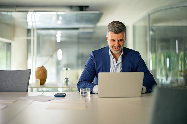 istock Smiling businessman working on laptop in modern office 2214551538