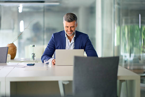 istock Smiling businessman working on laptop in modern office 2214551629