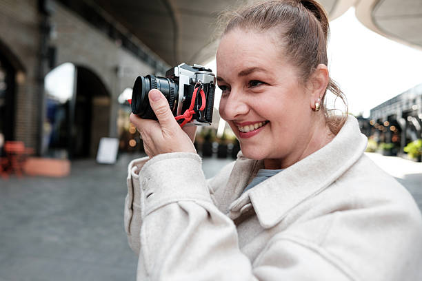 istock Photographer smiling and taking photos with analog camera in urban setting 2214551883