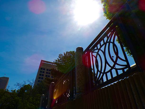 Railing in city with blue sky and sun.