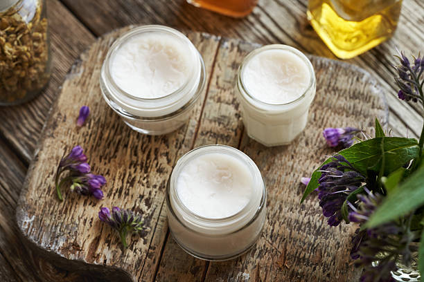istock Three jars of homemade comfrey root ointment made with rendered pork lard with fresh blooming Symphytum plant 2214558580