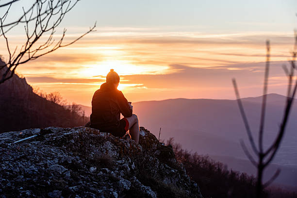 istock Mountaineer resting on mountain top at sunset, enjoying scenic view 2214559719