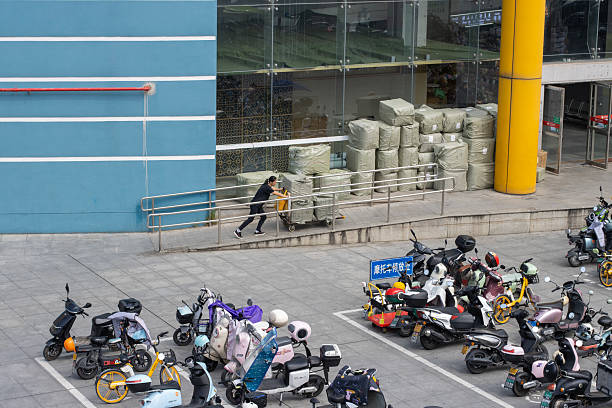Yiwu, Zhejiang, China - Oct 9, 2024: A saleswoman pushes a cart laden with goods at an entrance to the Yiwu International Trade Market, the largest wholesale market complex in China. Yiwu, a city in east China's Zhejiang Province, is known for being the world's biggest small commodities hub.