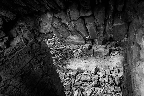 Crumbling stones form a haunting corridor leading to a desolate underground hideout. Shadows dance as dusk settles over the forgotten remnants of a once-thriving space filled with history.