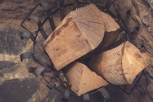 istock Rustic wooden logs stacked in an iron basket by a cozy fireplace in a quaint cabin setting during wintertime 2214573003
