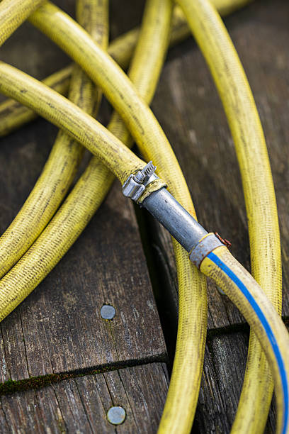 istock Yellow coiled hose with metal clamp on dock.. 2214573833