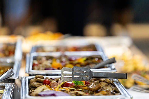 A vibrant buffet table displays a variety of dishes, including meats and vegetables. Salad ingredients and garnishes add freshness. Guests enjoy the warm atmosphere.