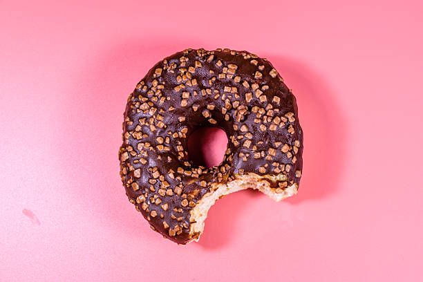 istock Bitten donut with chocolate glaze on top isolated on a pink background 2214576559