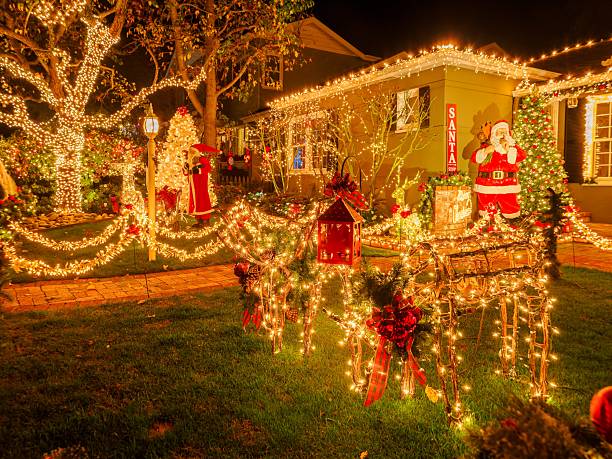 A charming house on Eucalyptus Avenue in San Carlos, California, is beautifully adorned with Christmas lights and decorations. The festive display includes a Santa Claus figure, reindeer, and a glowing Christmas tree, creating a magical holiday scene.
