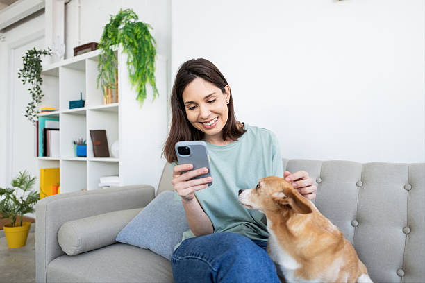 istock Woman enjoying smartphone while petting dog on couch 2214583293