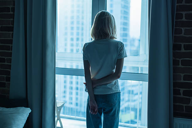 istock Young woman standing near window 2214584085