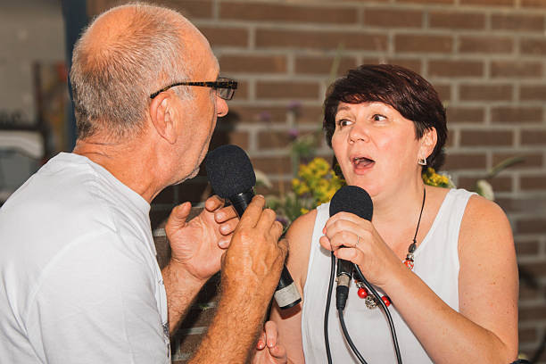 istock Vocal lessons. An elderly man shows a woman singing techniques with eye contact 2214594486