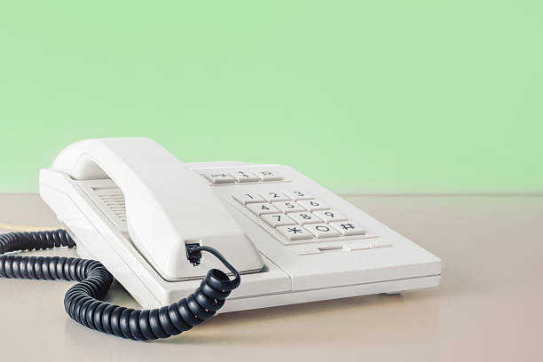 istock Desk phone 80s 90s on table against green wall copy space 2214594543