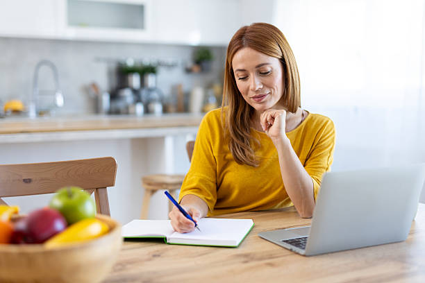 istock Engaged Woman Writing Thoughtfully in Bright Home Kitchen 2214594596