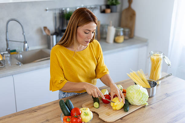 istock Chopping Vegetables: Woman in Bright Kitchen Preparing Food 2214594609