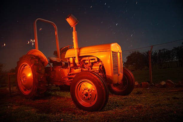A classic grey Ferguson tractor positioned in a rural paddock beneath a canopy of stars.