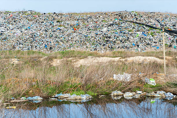 istock Environmental Pollution: Large Landfill Overflowing with Waste and Garbage Reflected in a Polluted Water Source 2214597013
