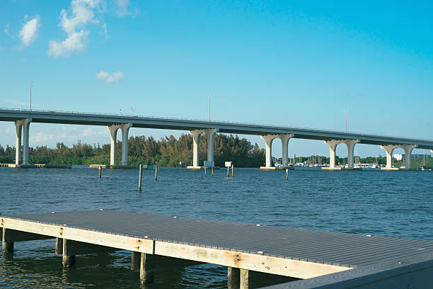 istock Wooden pier extending into a tranquil bay with a bridge in the background 2214603591