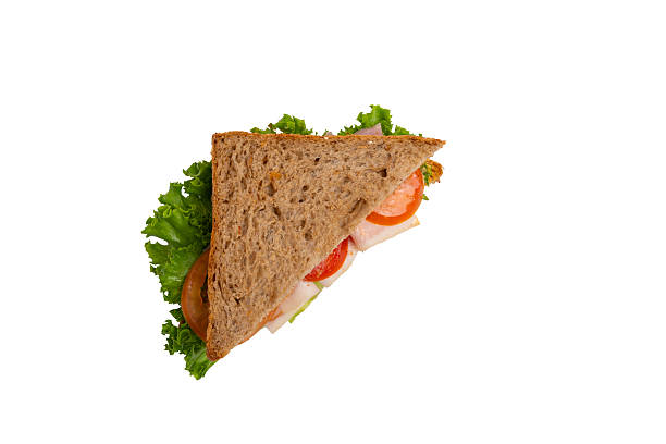 istock A ham sandwich with lettuce, tomato, and ham on whole-wheat bread is isolated on a white background. 2214606632