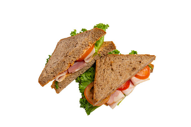 istock Two ham sandwiches with lettuce, tomato, and ham on whole-wheat bread are isolated on a white background. 2214606656