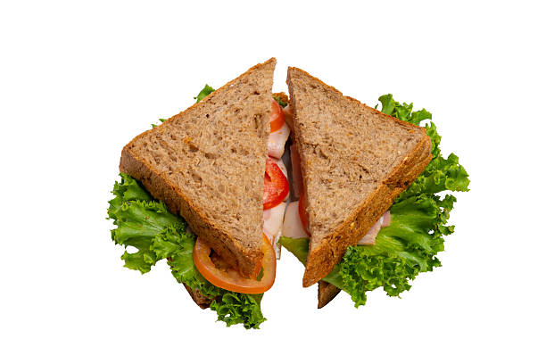 istock Two ham sandwiches with lettuce, tomato, and ham on whole-wheat bread are isolated on a white background. 2214606661