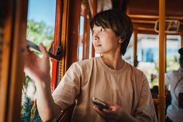 istock Thoughtful Asian passenger gazes outside during a vintage trolley ride 2214611955