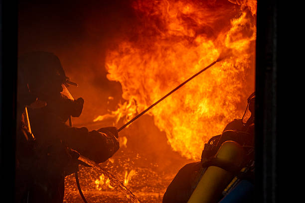 istock Firefighter Rescue team training fire fighting extinguisher. Teamwork Firefighter fighting with flame using fire hose chemical water foam spray engine. Fireman teams wear hard hat safety uniform 2214612797