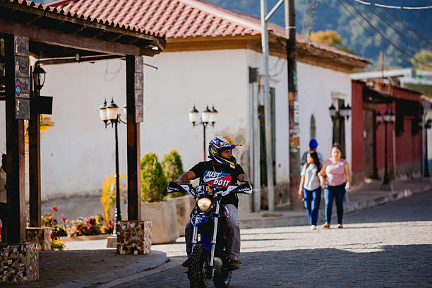 A man riding a motorcycle in El Salvador, in 2025. Photographed using a long lens in the early moring hours.