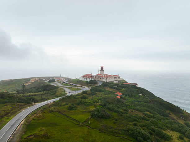 Distant view of winding road and red-roof lighthouse on coastal cliffs