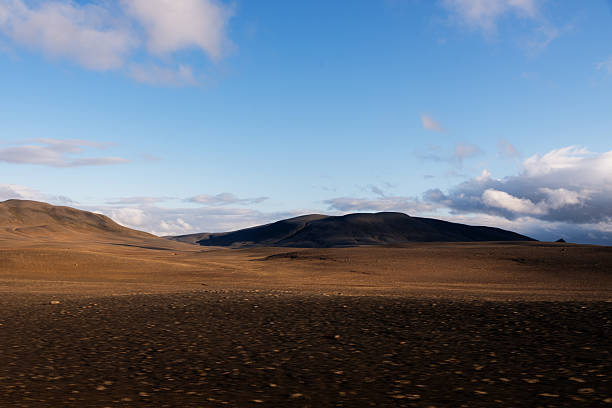A sweeping view of Iceland's volcanic highlands under soft golden hour light, showcasing the barren yet captivating terrain beneath a clear blue sky.