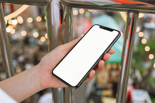 Hand holding smartphone with blank screen for graphic display montage on outdoors background, mockup display for lifestyle and wireless technology.