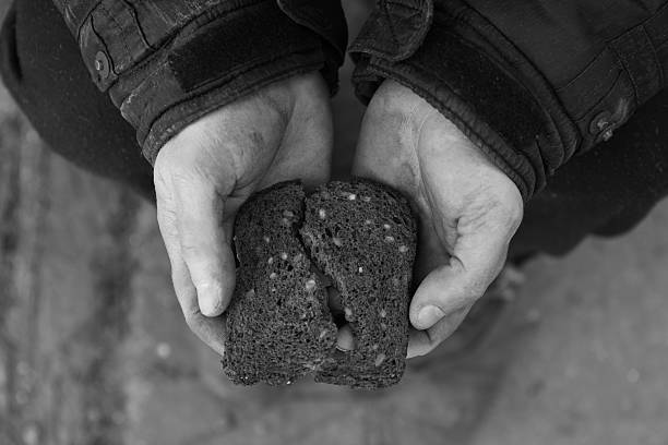 istock Poor homeless man holding piece of bread outdoors, top view. Black and white effect 2214619509