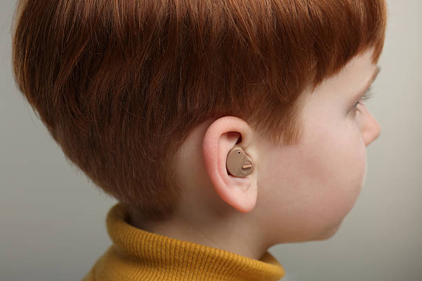 istock Little boy with hearing aid on grey background, closeup 2214619637