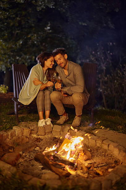 istock Loving couple toasting by the fire during the night in the backyard. 2214620037