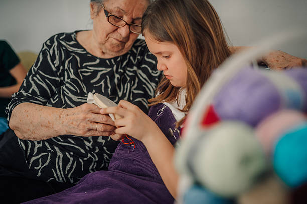 Grandmother and granddaughter enjoying quality time together, learning the art of cross-stitch embroidery