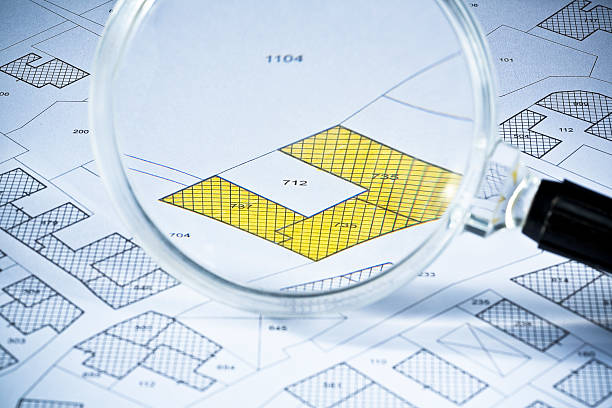 istock Imaginary cadastral map with buildings, land parcel and vacant plot - land and property registry and real estate property concept illustration seen through a magnifying glass 2214632695