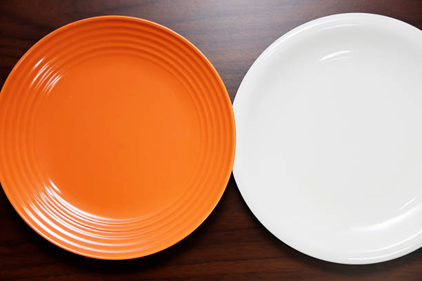 istock Empty orange and white plate on wooden table background. 2214633999