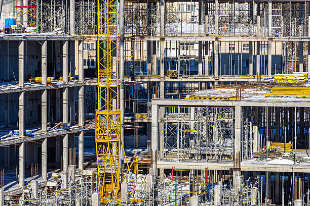 istock Tall building under construction with scaffolds,Freestanding tower crane on a building site.Building construction site work against blue sky 2214635886