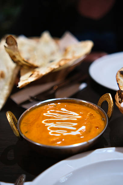 A bowl of creamy tikka masala chicken, rich in orange-red sauce.
