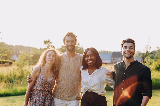 istock Four happy friends embracing in a sunny field 2214635949