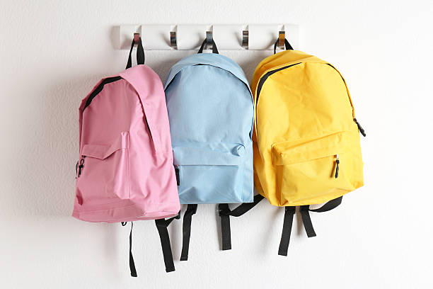 Bright backpacks hanging on white wall. Back to school