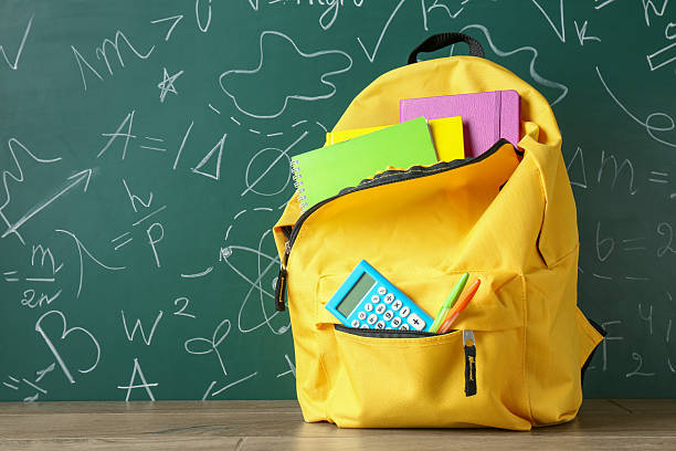 istock Backpack with different school stationery on wooden table against green chalkboard 2214636223