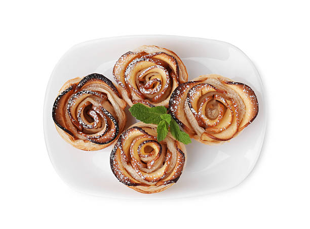 Freshly baked apple roses with mint isolated on white, top view. Puff pastry